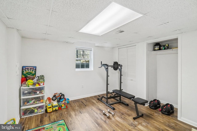 exercise area with hardwood / wood-style flooring and a drop ceiling