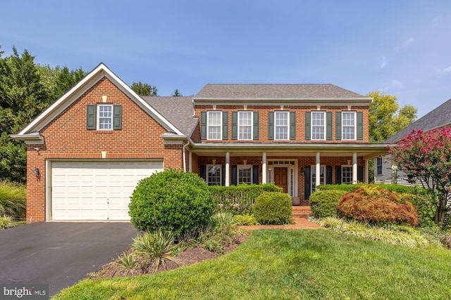 colonial inspired home featuring a porch, a garage, and a front lawn