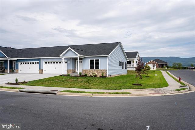 single story home with a garage, a mountain view, and a front yard