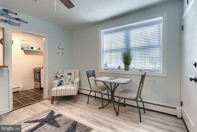 sitting room featuring wood-type flooring, a baseboard heating unit, and ceiling fan