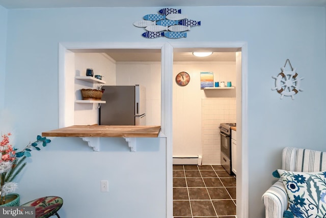 kitchen featuring stainless steel appliances, a baseboard heating unit, and dark tile patterned flooring