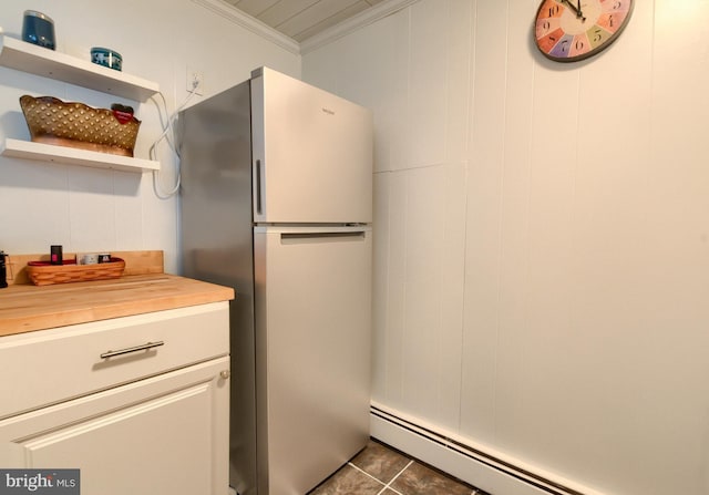 kitchen with stainless steel refrigerator, baseboard heating, ornamental molding, wood counters, and dark tile patterned flooring