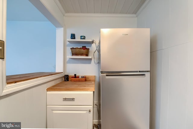 kitchen with ornamental molding, stainless steel fridge, butcher block counters, and white cabinets