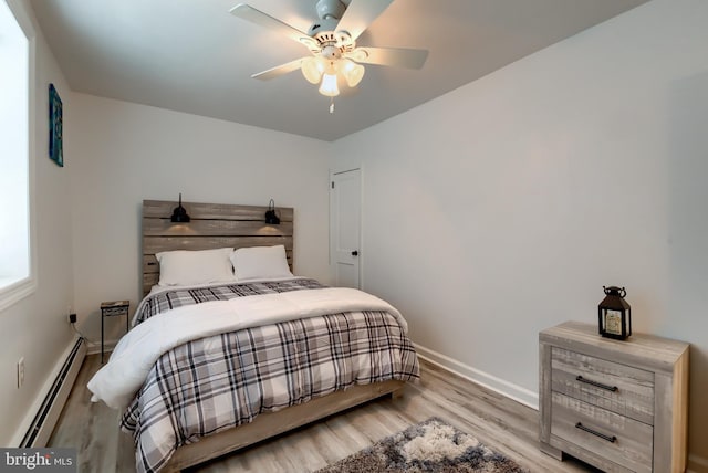 bedroom with a baseboard heating unit, ceiling fan, and light wood-type flooring