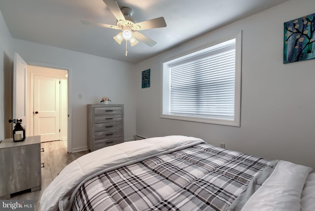 bedroom featuring ceiling fan, a baseboard radiator, and light wood-type flooring