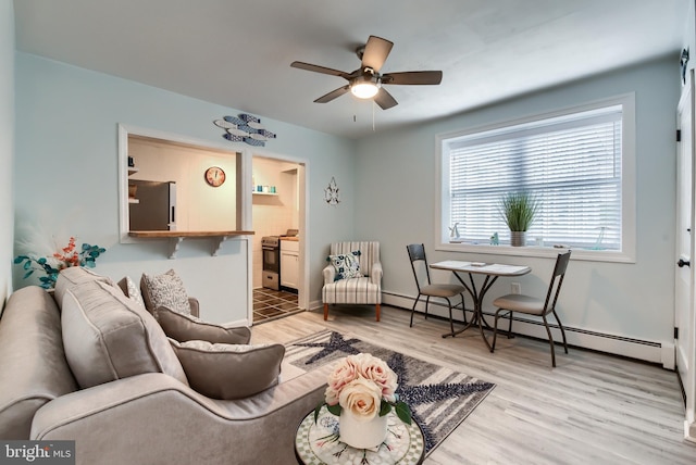 living room with ceiling fan, light wood-type flooring, and a baseboard heating unit