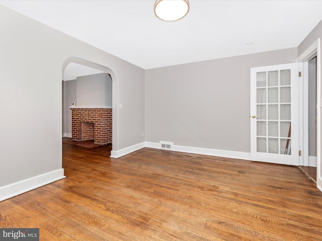 unfurnished room with a brick fireplace and hardwood / wood-style floors