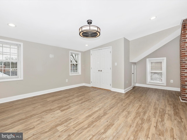 unfurnished living room with vaulted ceiling, plenty of natural light, and light hardwood / wood-style floors