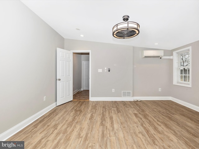 empty room with a wall unit AC and light hardwood / wood-style flooring