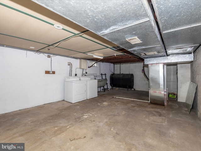 basement with sink, washing machine and dryer, and heating unit