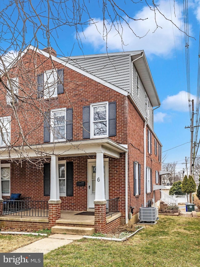 view of front of property with central AC unit, covered porch, and a front yard