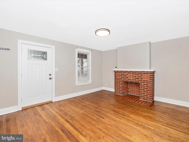 unfurnished living room featuring a brick fireplace and hardwood / wood-style floors