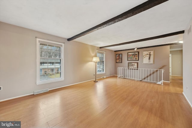 spare room with beam ceiling and light hardwood / wood-style flooring