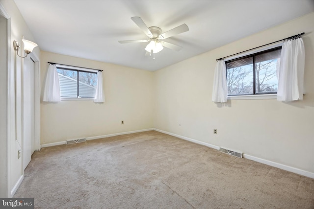 carpeted spare room with ceiling fan and plenty of natural light