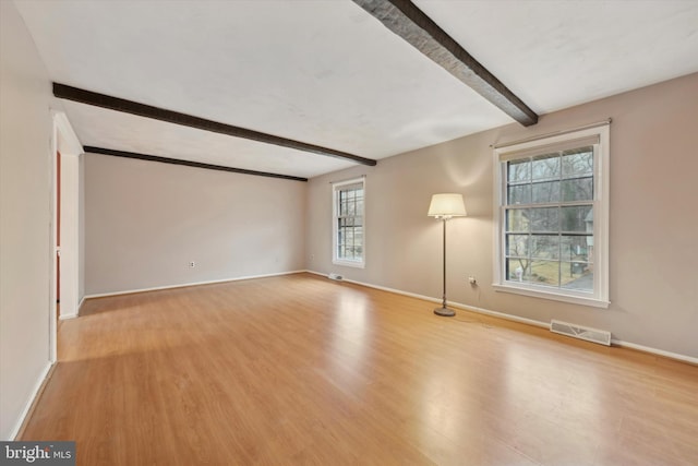 empty room featuring beam ceiling and light wood-type flooring