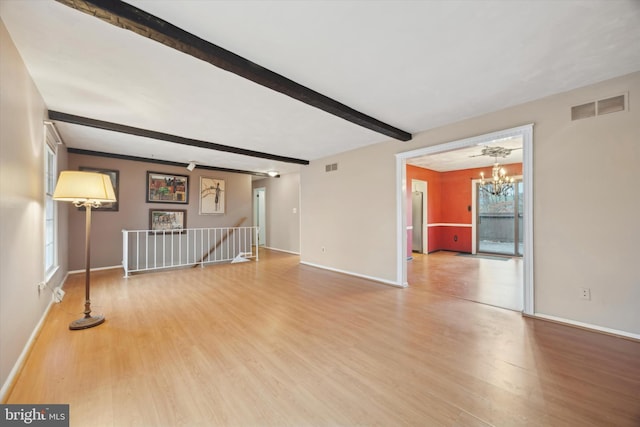 unfurnished living room featuring beamed ceiling, wood-type flooring, and an inviting chandelier