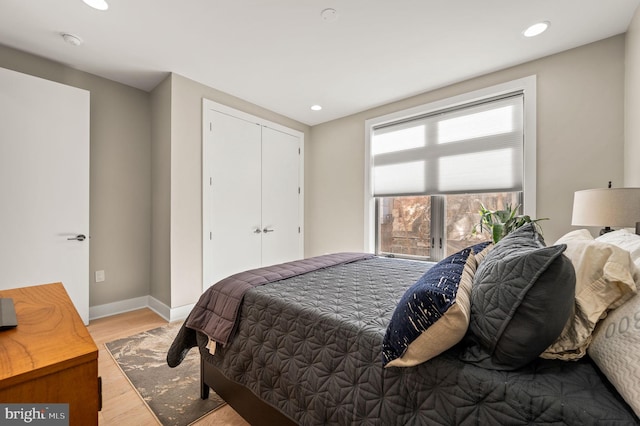 bedroom with a closet, baseboards, wood finished floors, and recessed lighting