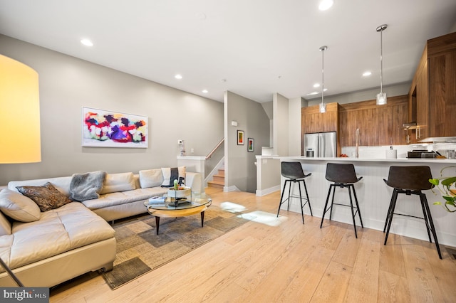 living area with recessed lighting, light wood-style flooring, and stairs