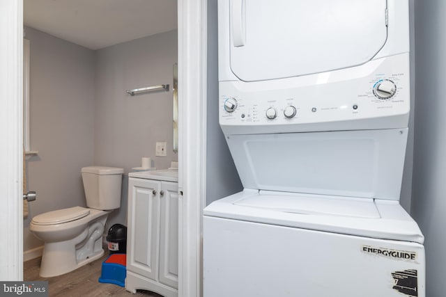 washroom with hardwood / wood-style flooring and stacked washer and dryer