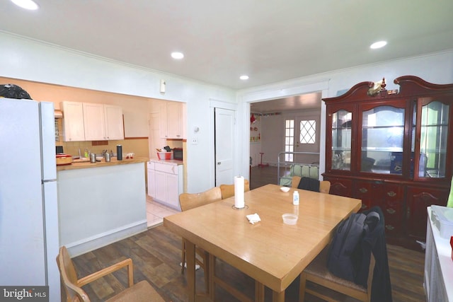 dining space with dark wood-type flooring, recessed lighting, and crown molding