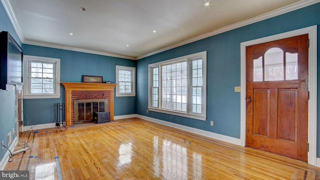 entryway with crown molding, plenty of natural light, light wood-type flooring, and a fireplace