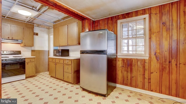 kitchen with white range with gas stovetop, stainless steel refrigerator, and wood walls