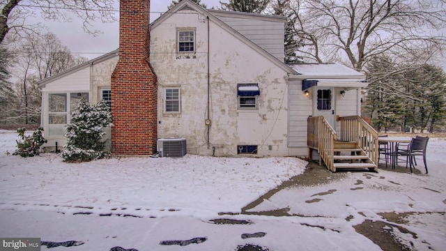 snow covered back of property featuring central air condition unit