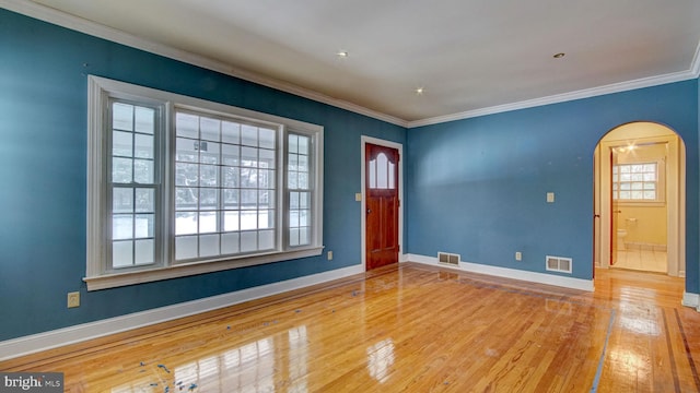 spare room featuring crown molding, a healthy amount of sunlight, and light wood-type flooring