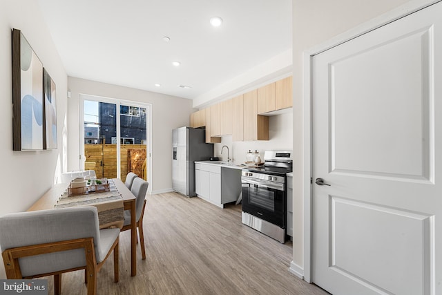 kitchen featuring light wood finished floors, stainless steel appliances, recessed lighting, light countertops, and baseboards