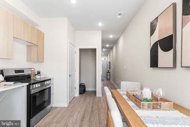 kitchen with light wood-style floors, light countertops, stainless steel electric range, light brown cabinetry, and modern cabinets