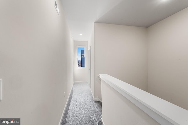 corridor featuring light carpet, baseboards, and an upstairs landing