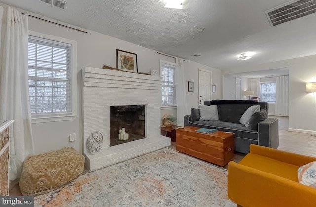 living room with a brick fireplace and a textured ceiling