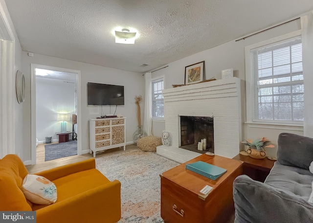 living room featuring a brick fireplace and a textured ceiling