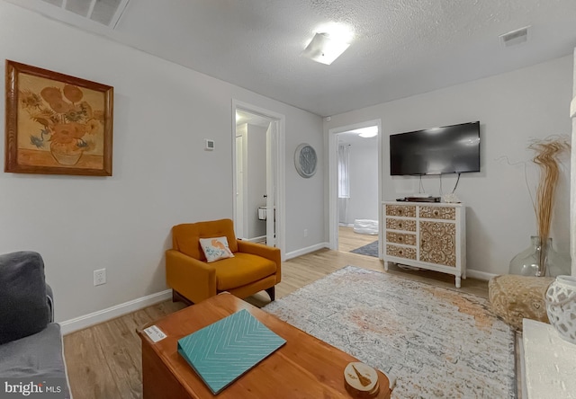 living room with light hardwood / wood-style floors and a textured ceiling