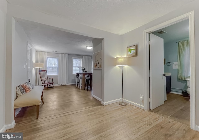 hallway featuring light hardwood / wood-style floors and a textured ceiling