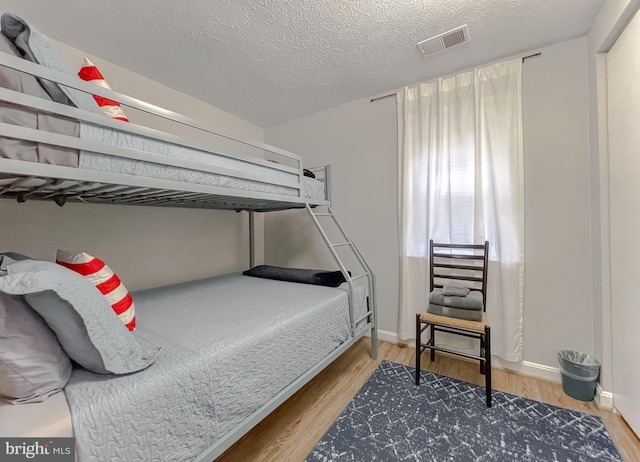 bedroom with hardwood / wood-style floors and a textured ceiling