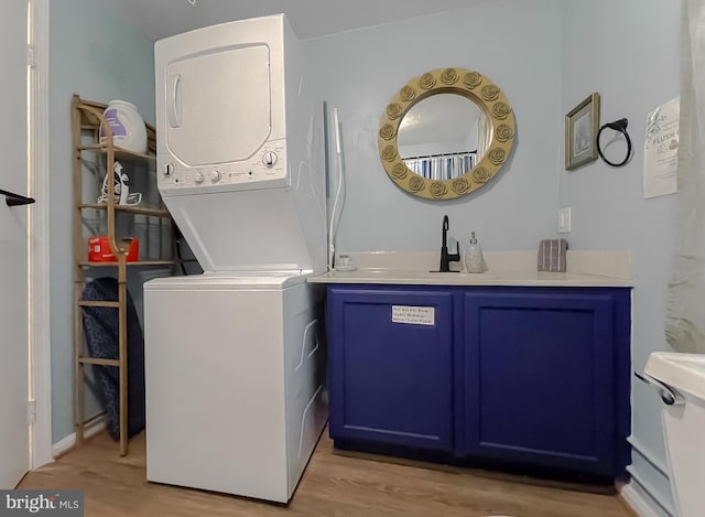 washroom with stacked washer and clothes dryer and light hardwood / wood-style floors