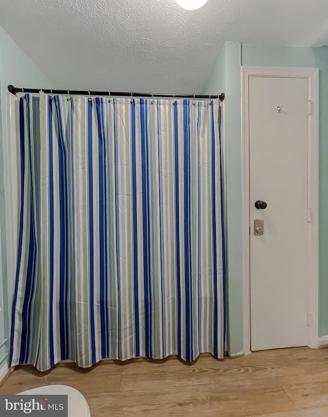 interior space with hardwood / wood-style flooring, walk in shower, and a textured ceiling