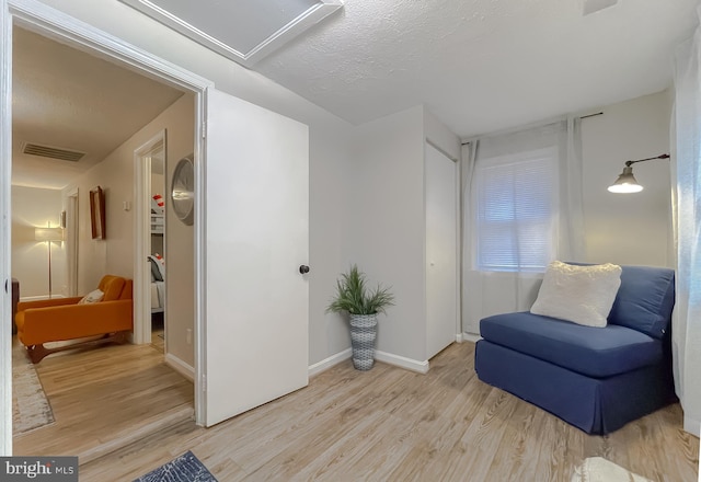 living area featuring light hardwood / wood-style flooring and a textured ceiling