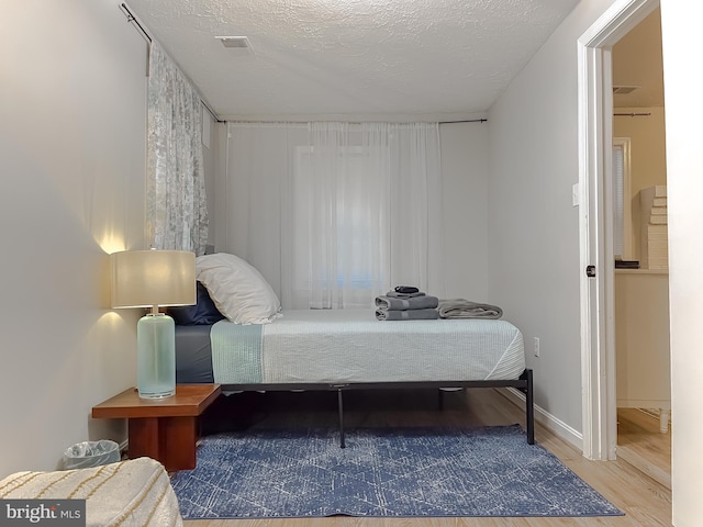 bedroom with hardwood / wood-style floors and a textured ceiling