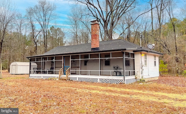 back of house with a storage shed and a sunroom