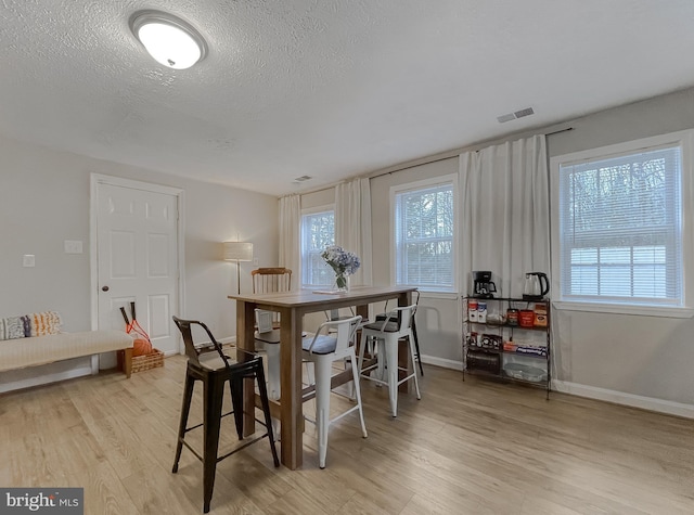 dining area with a textured ceiling and light wood-type flooring