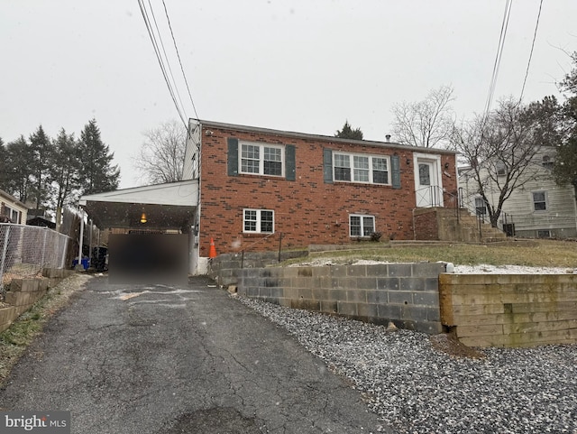 view of front of property featuring driveway, fence, a carport, and brick siding