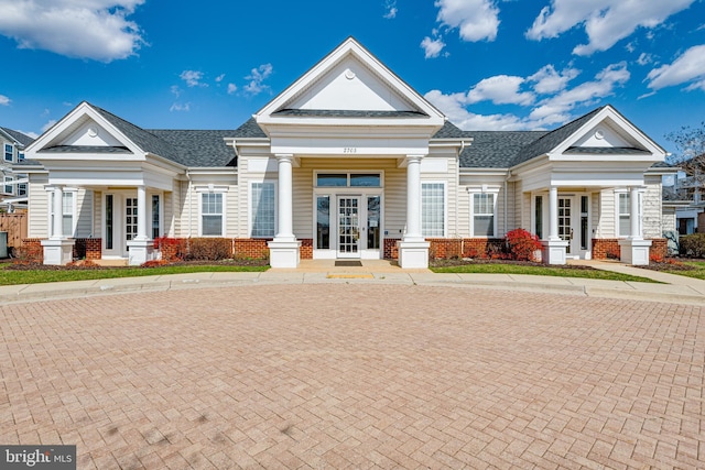 view of front of property featuring a shingled roof, french doors, and brick siding