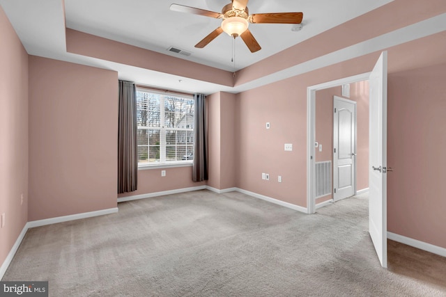 unfurnished room with baseboards, visible vents, a ceiling fan, a raised ceiling, and carpet flooring