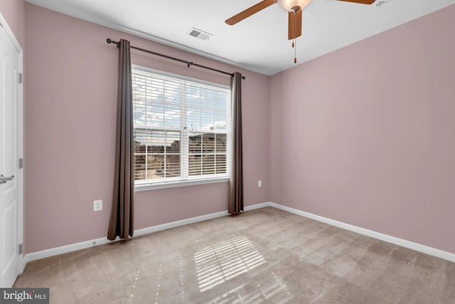 carpeted empty room with baseboards, visible vents, and a ceiling fan