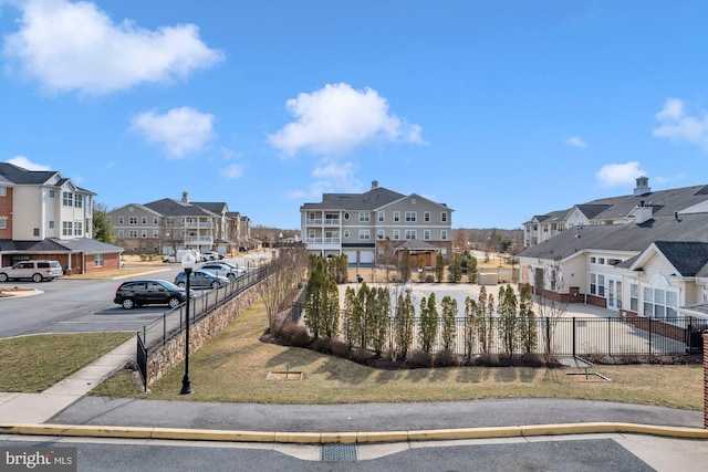 view of front of house with a residential view, fence, and uncovered parking