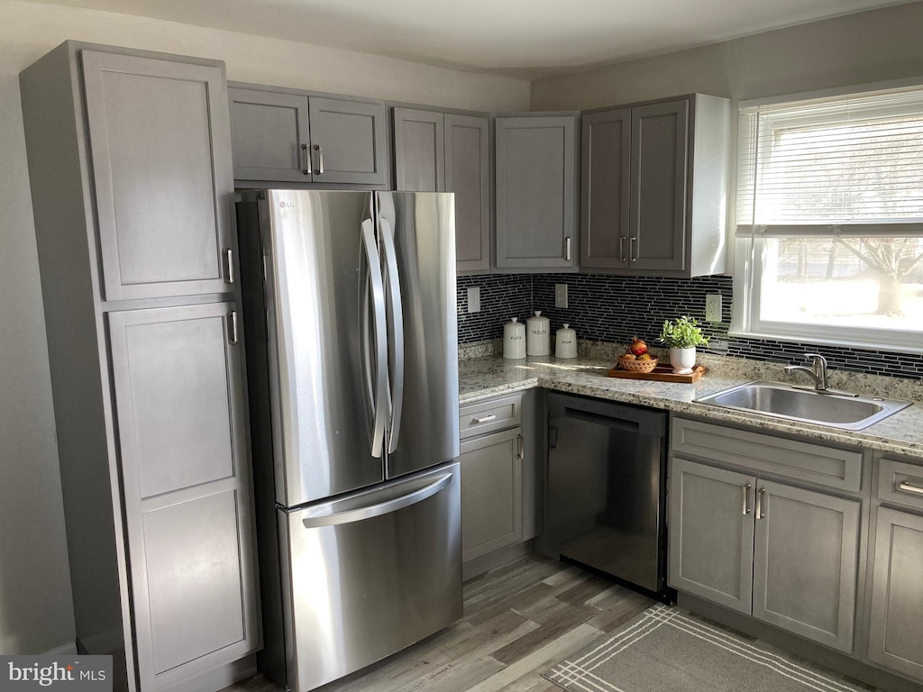 kitchen with dishwasher, a sink, freestanding refrigerator, and gray cabinetry