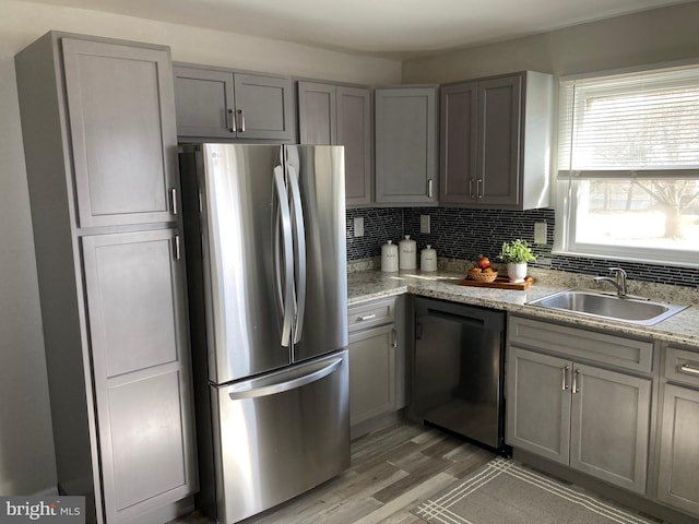 kitchen with dishwasher, a sink, freestanding refrigerator, and gray cabinetry