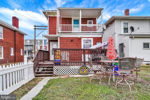 rear view of house with a wooden deck and a lawn